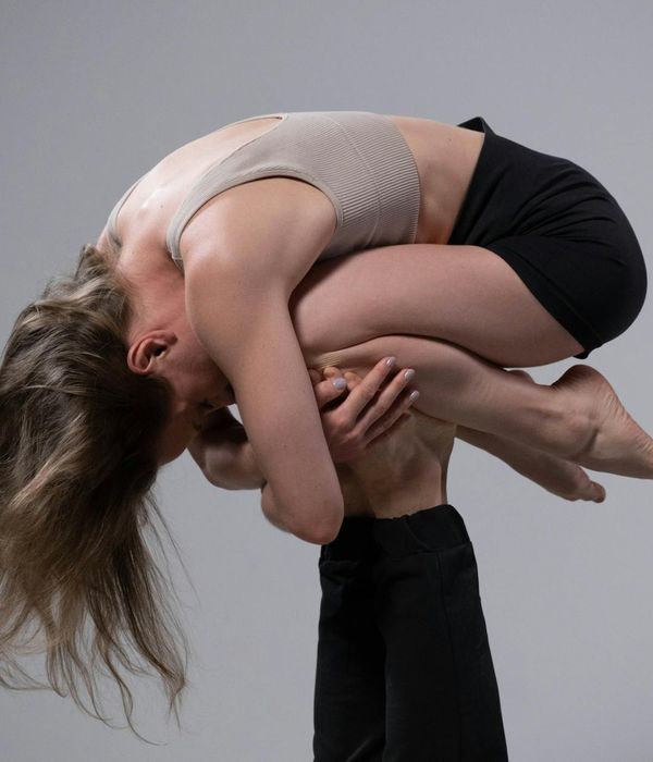 Woman performing a dynamic stretching movement in a minimalist studio.